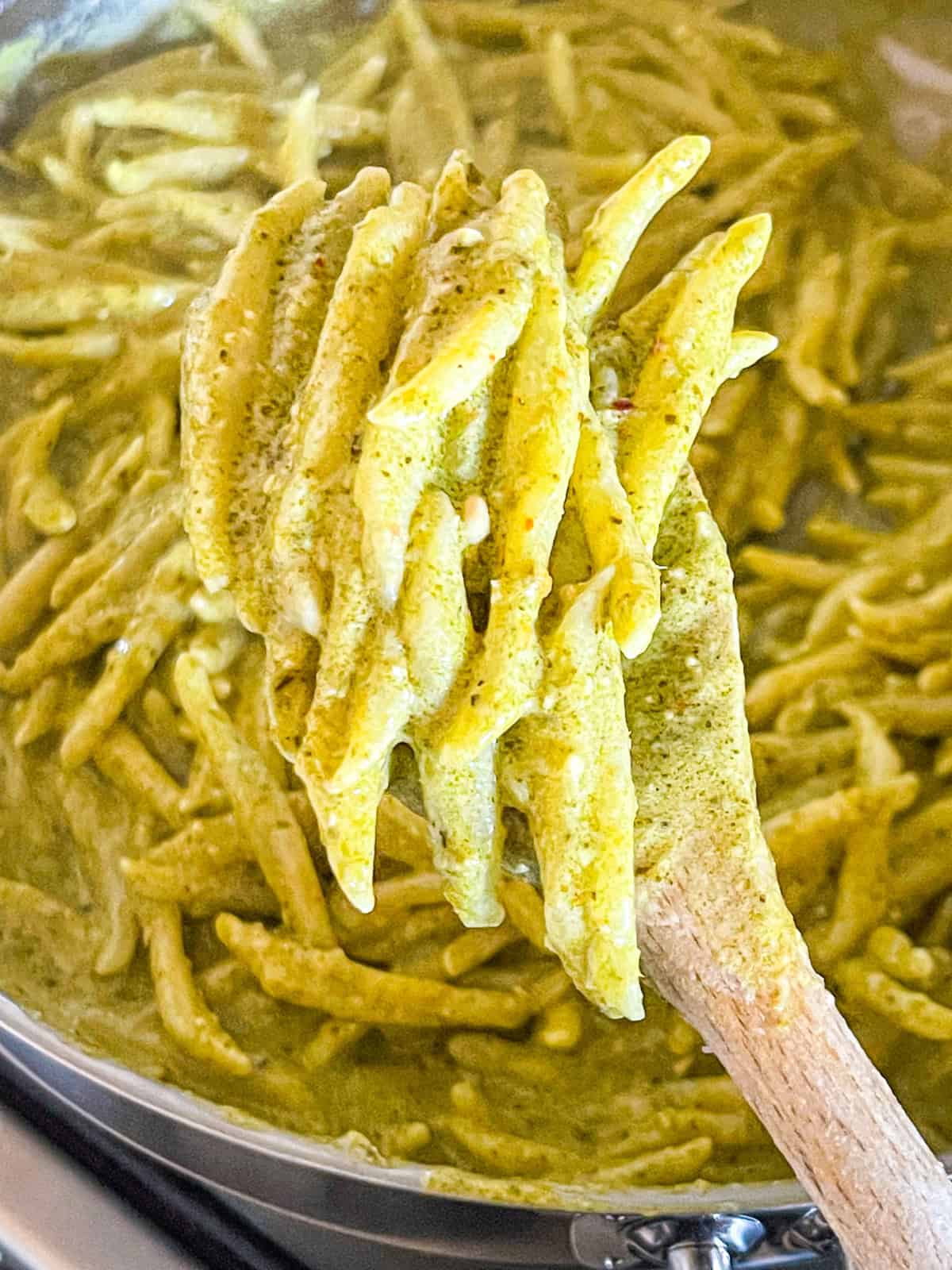Cooked pasta in a skillet with a spoon.