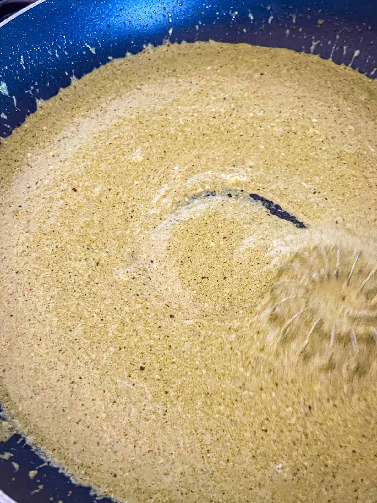 Pesto sauce whisk in a skillet.