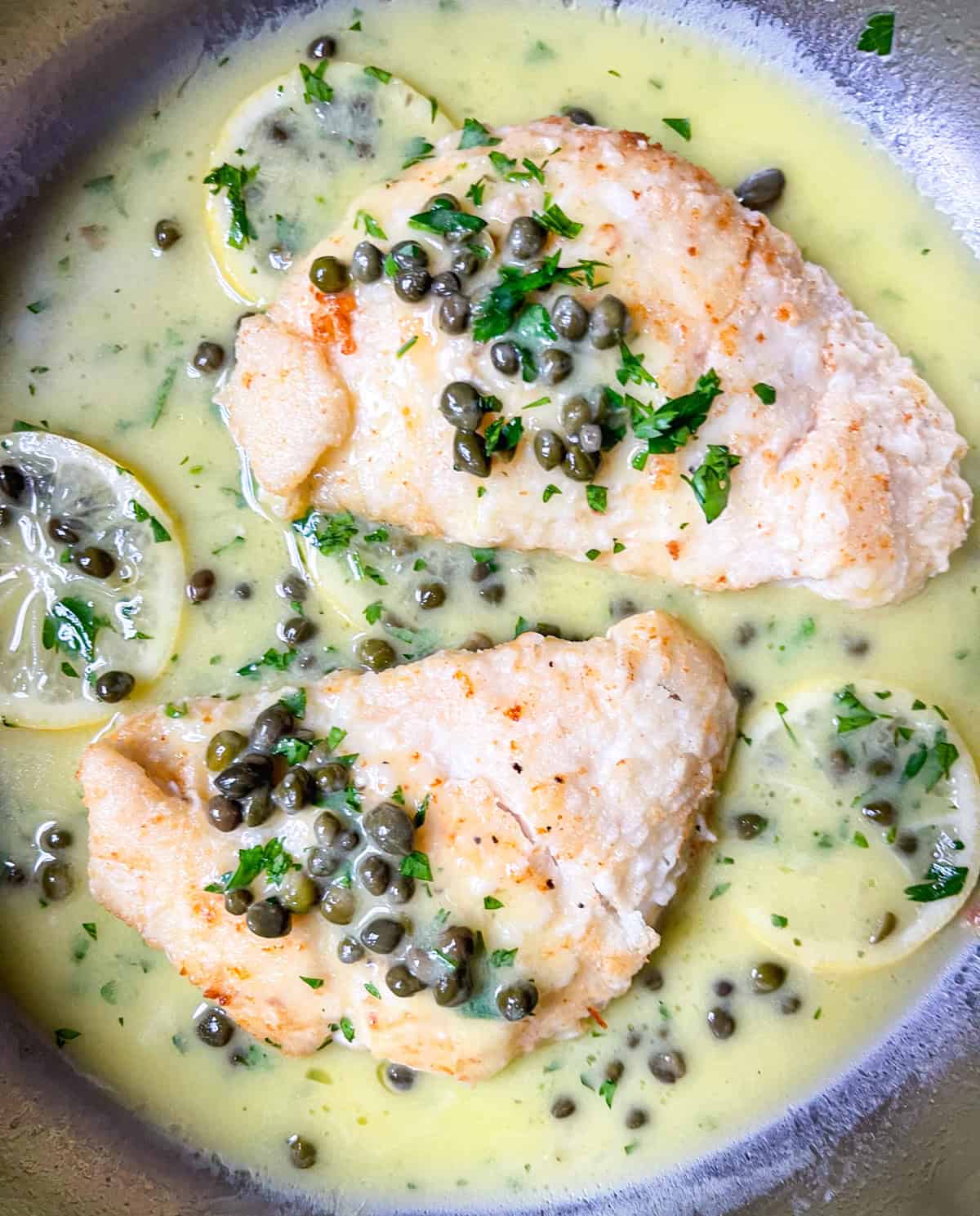 2 pieces of halibut cheeks in lemon piccata sauce.