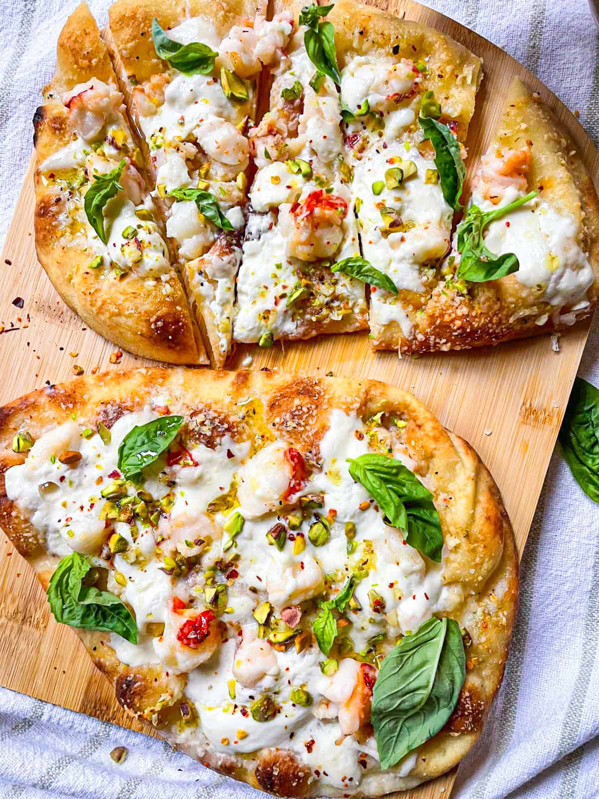 2 lobster pizzas. one sliced and one whole.