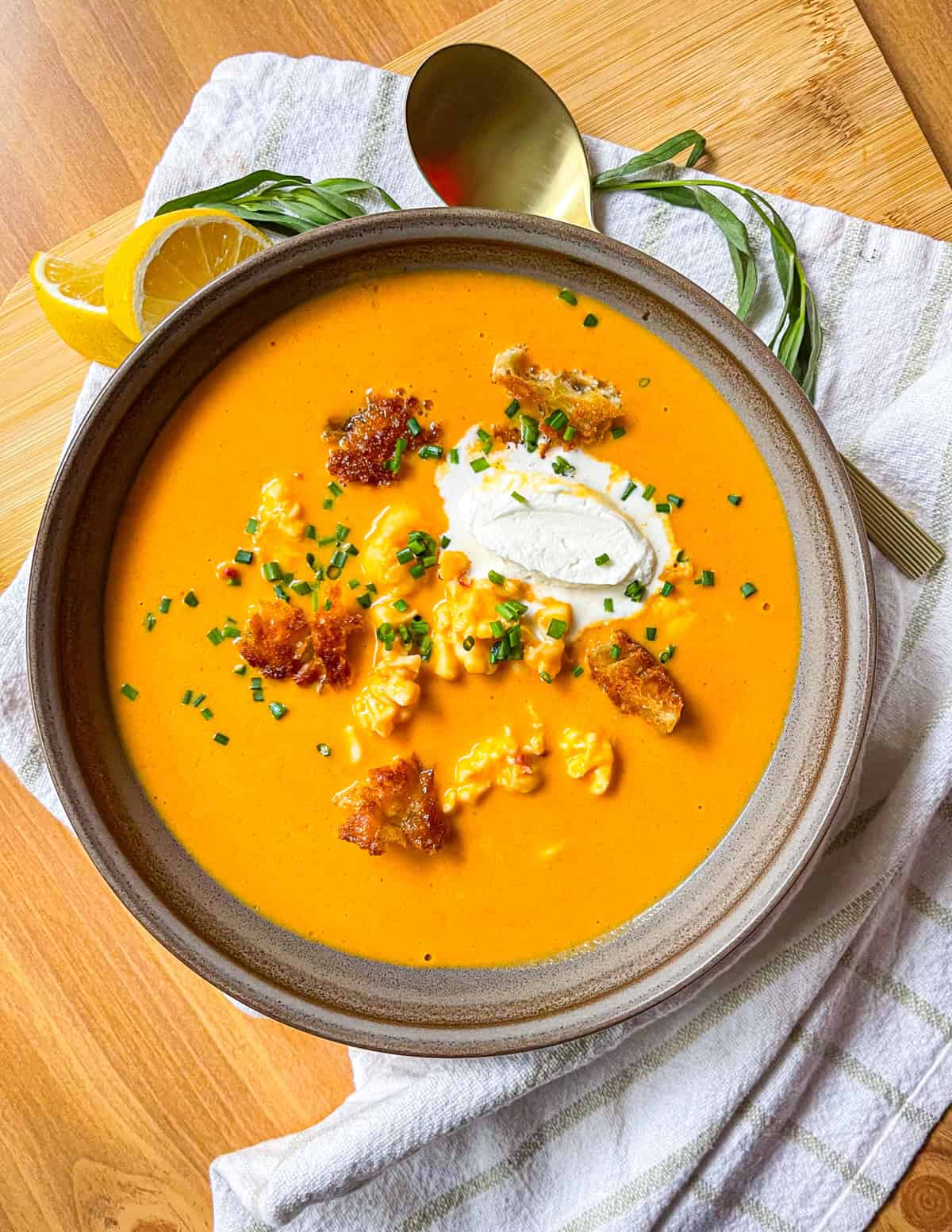 Lobster bisque in a bowl on a table and garnished with cream and crotons.