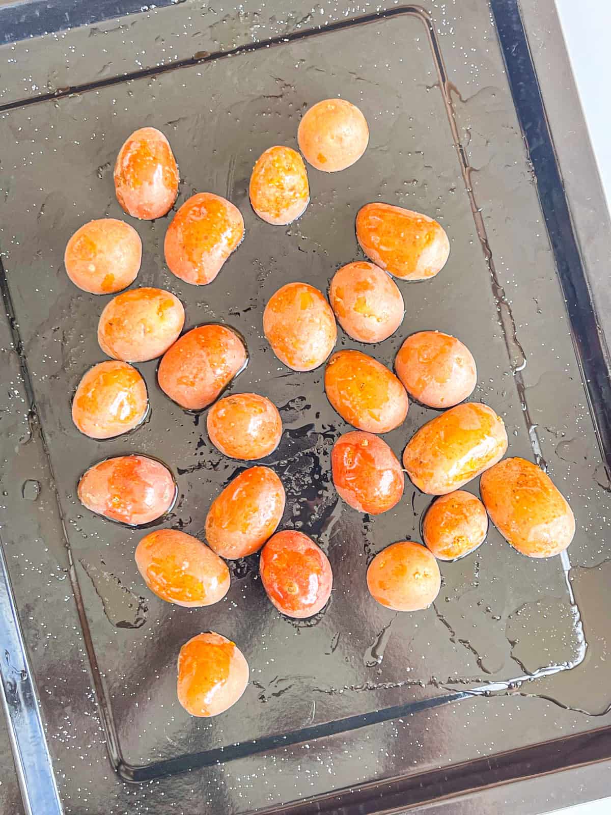 Potatoes cut in half on a sheet tray.