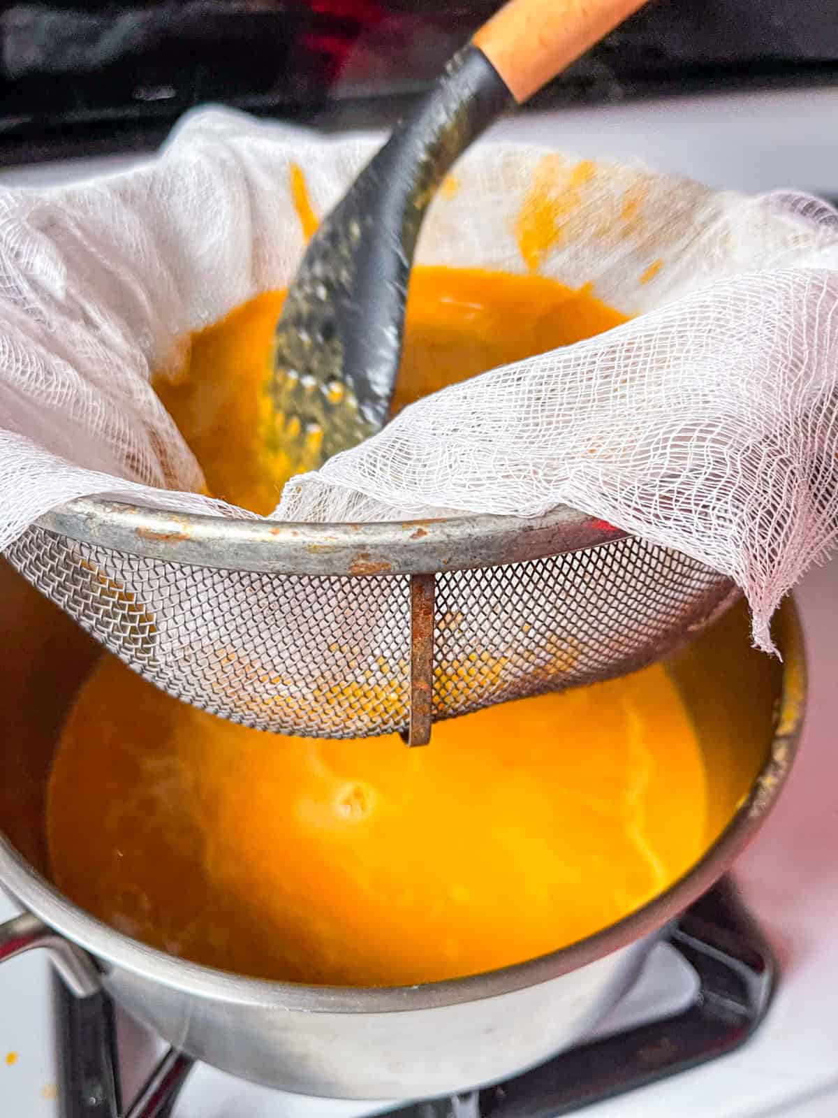 sieving bisque through the cheese cloth with a spoon.