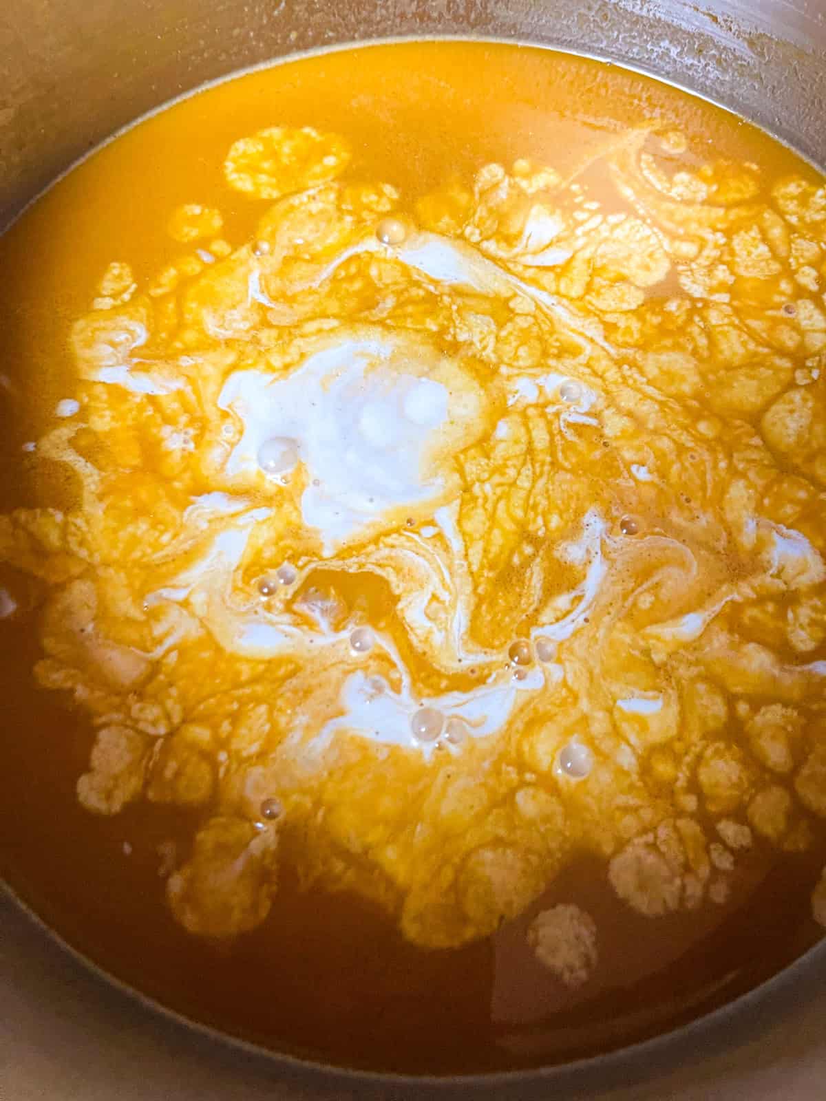 Cream added to shrimp bisque.