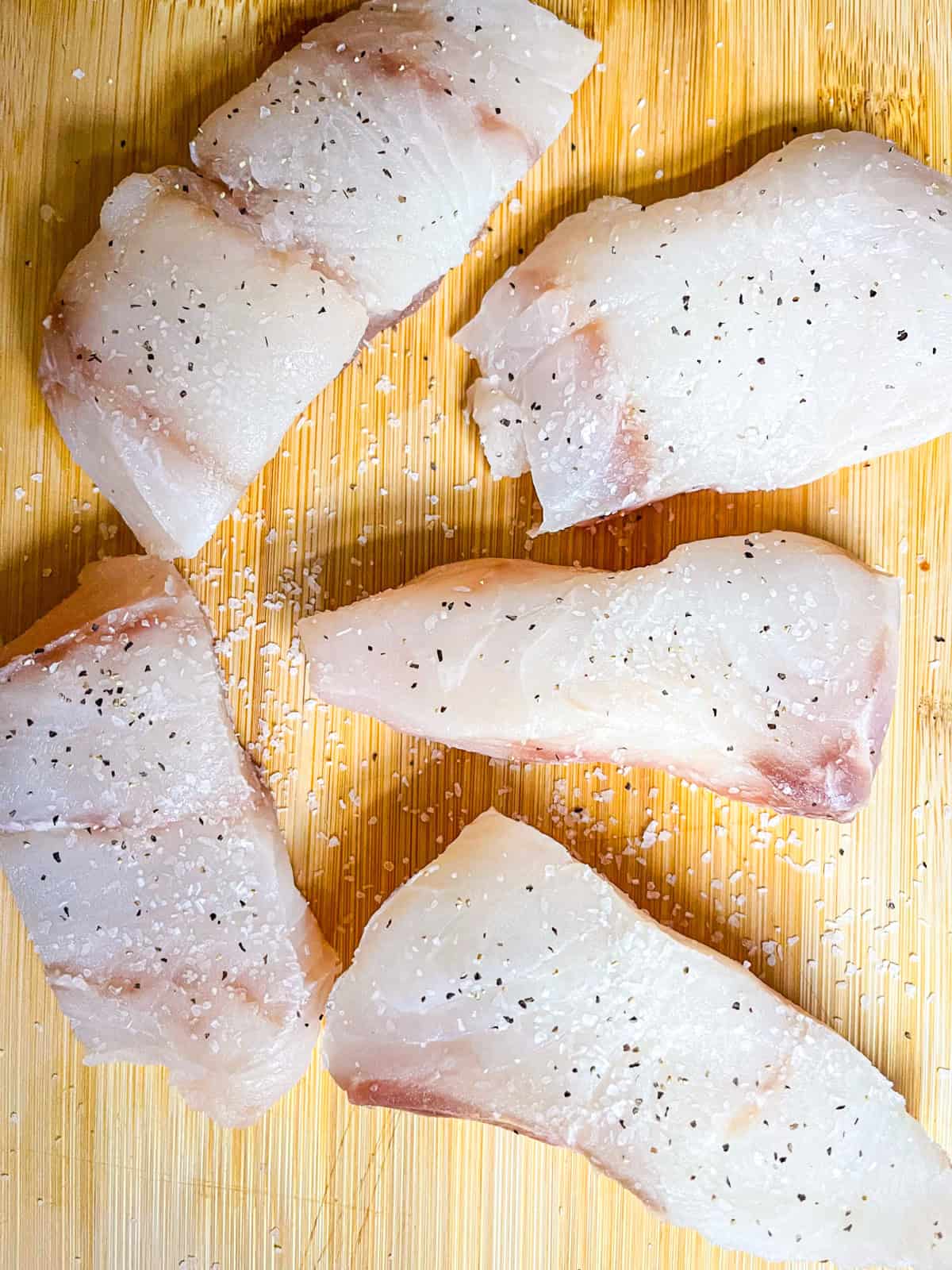 Seasoned white fish on a plank.