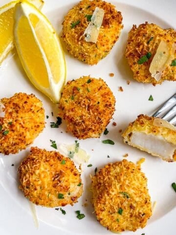 plate of crunchy, coated air fryer sea scallops with panko and parmesan, garnished with two lemon wedges.