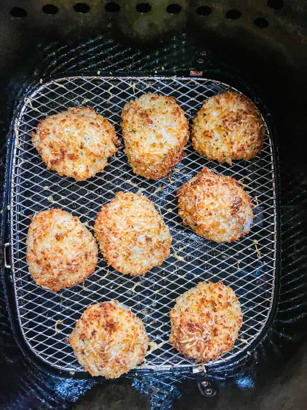 8 pieces of breaded cooked scallops in an air fryer.