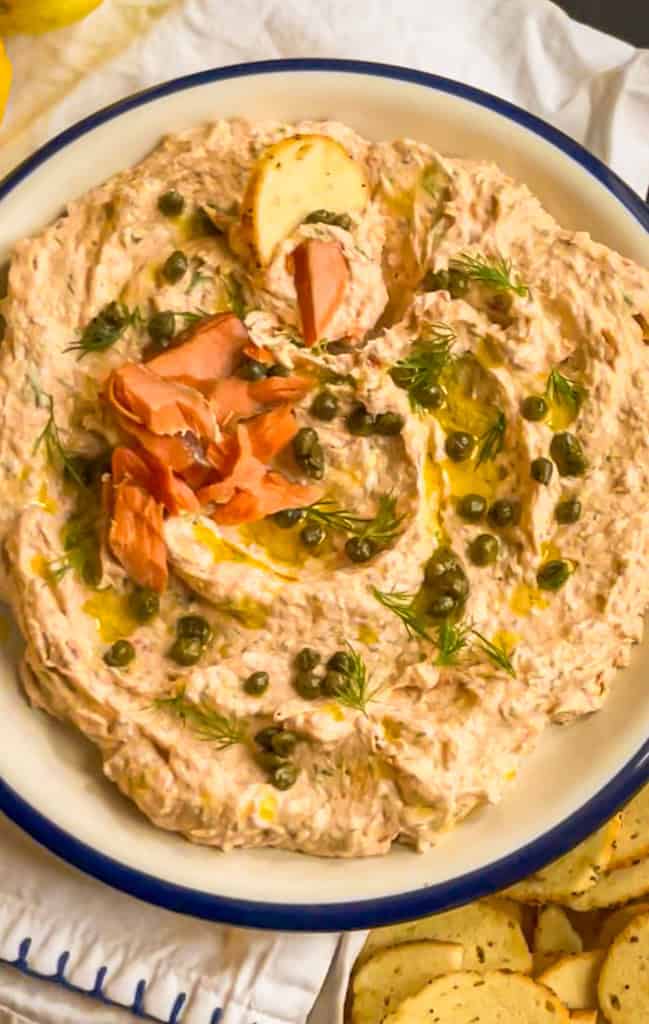 smoked salmon dip garnished with olive oil, capers, dill and smoked salmon flakes.