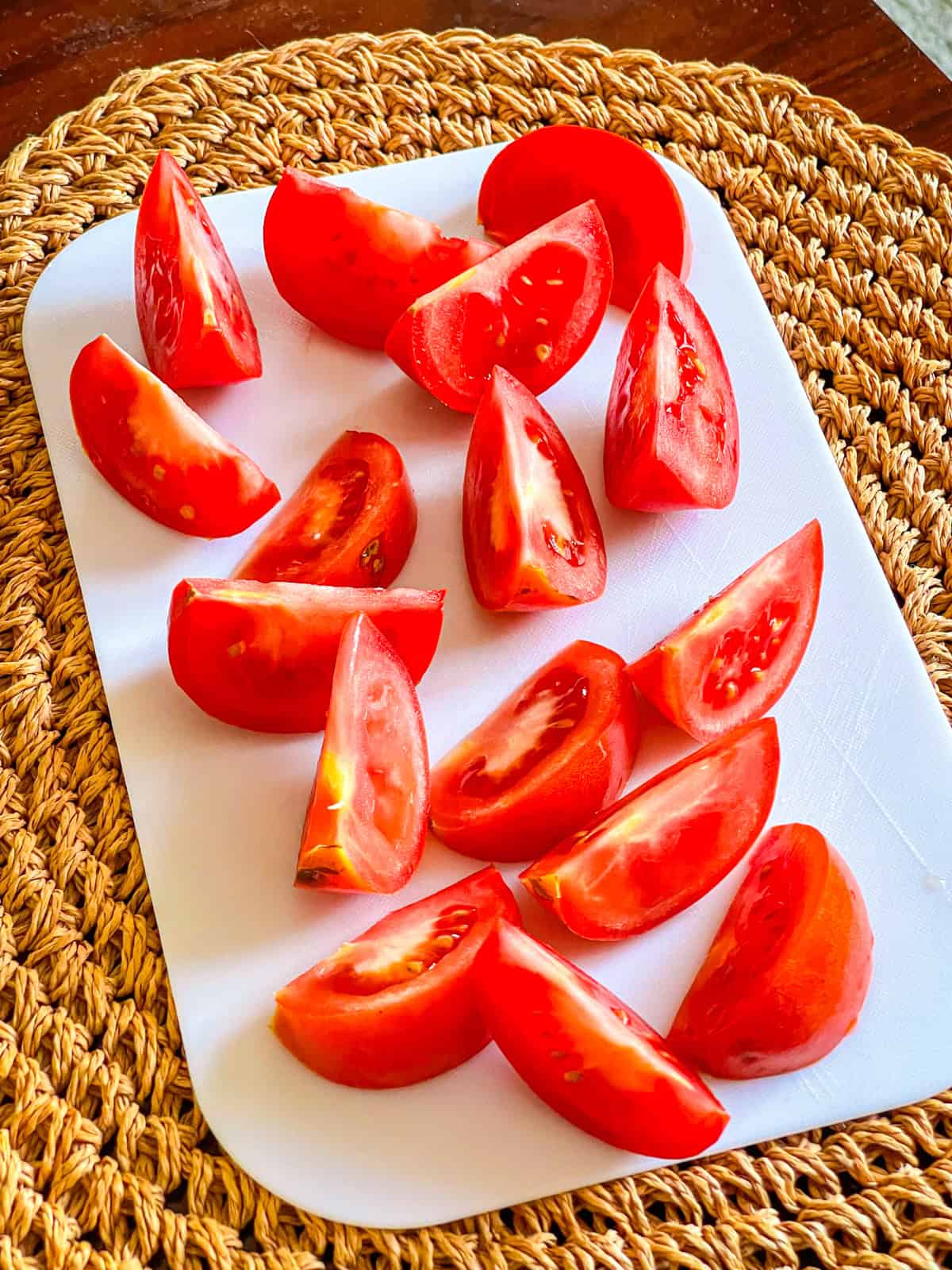tomatoes cut into wedegs on a board
