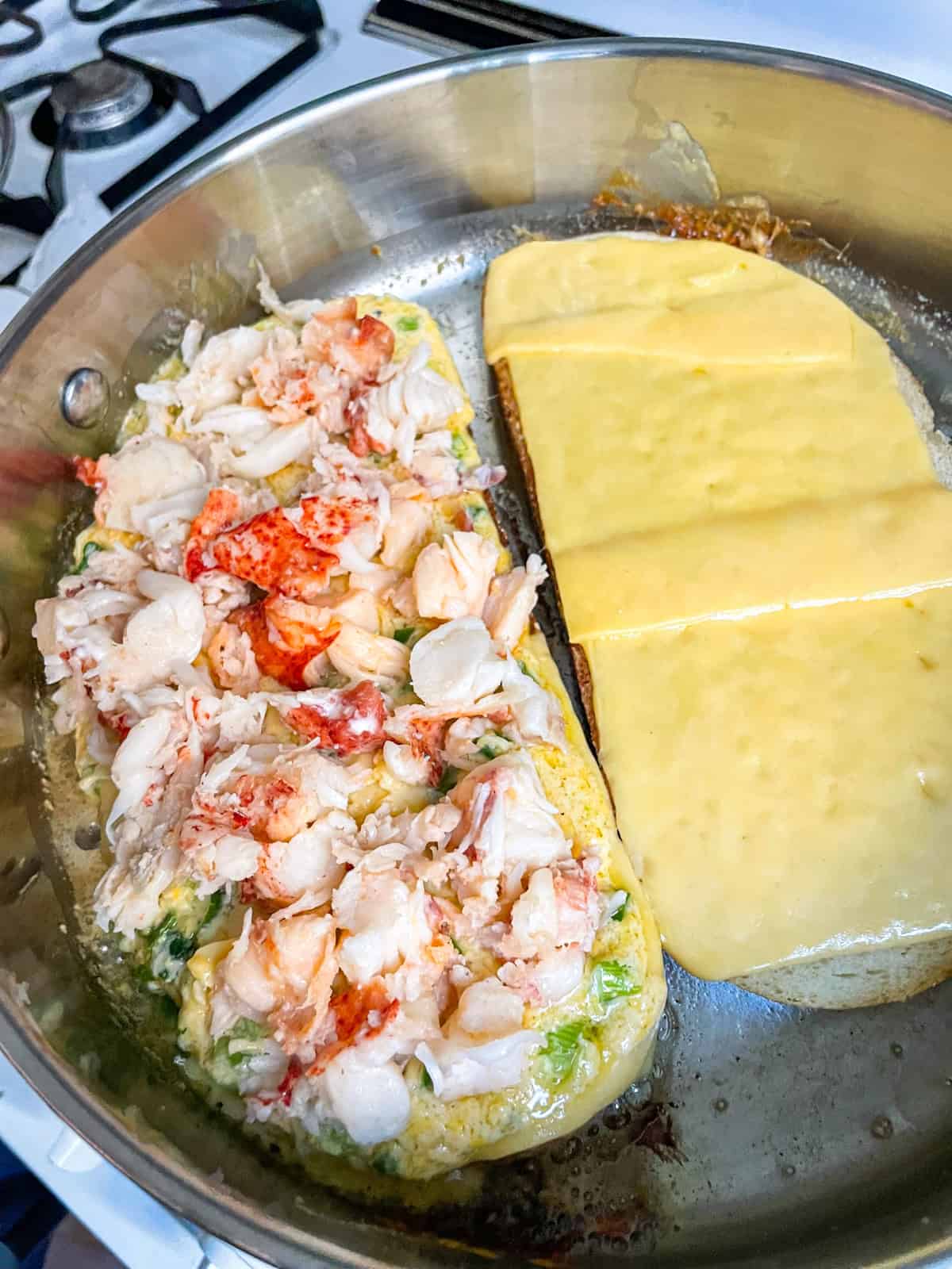 Lobster, mix and cheese laid out on bread in a skillet.