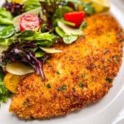 crispy breaded halibut cheek cutlet served with a fresh salad, parmesan cheese and lemon wedges.