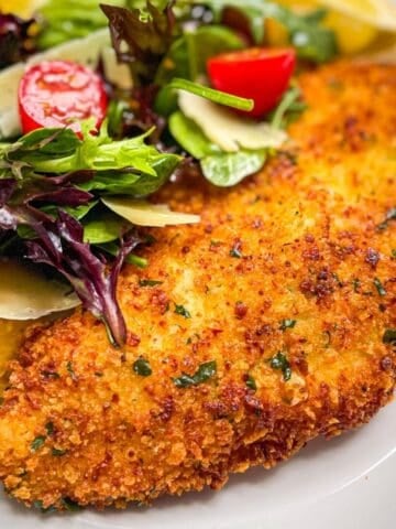 crispy breaded halibut cheek cutlet served with a fresh salad, parmesan cheese and lemon wedges.