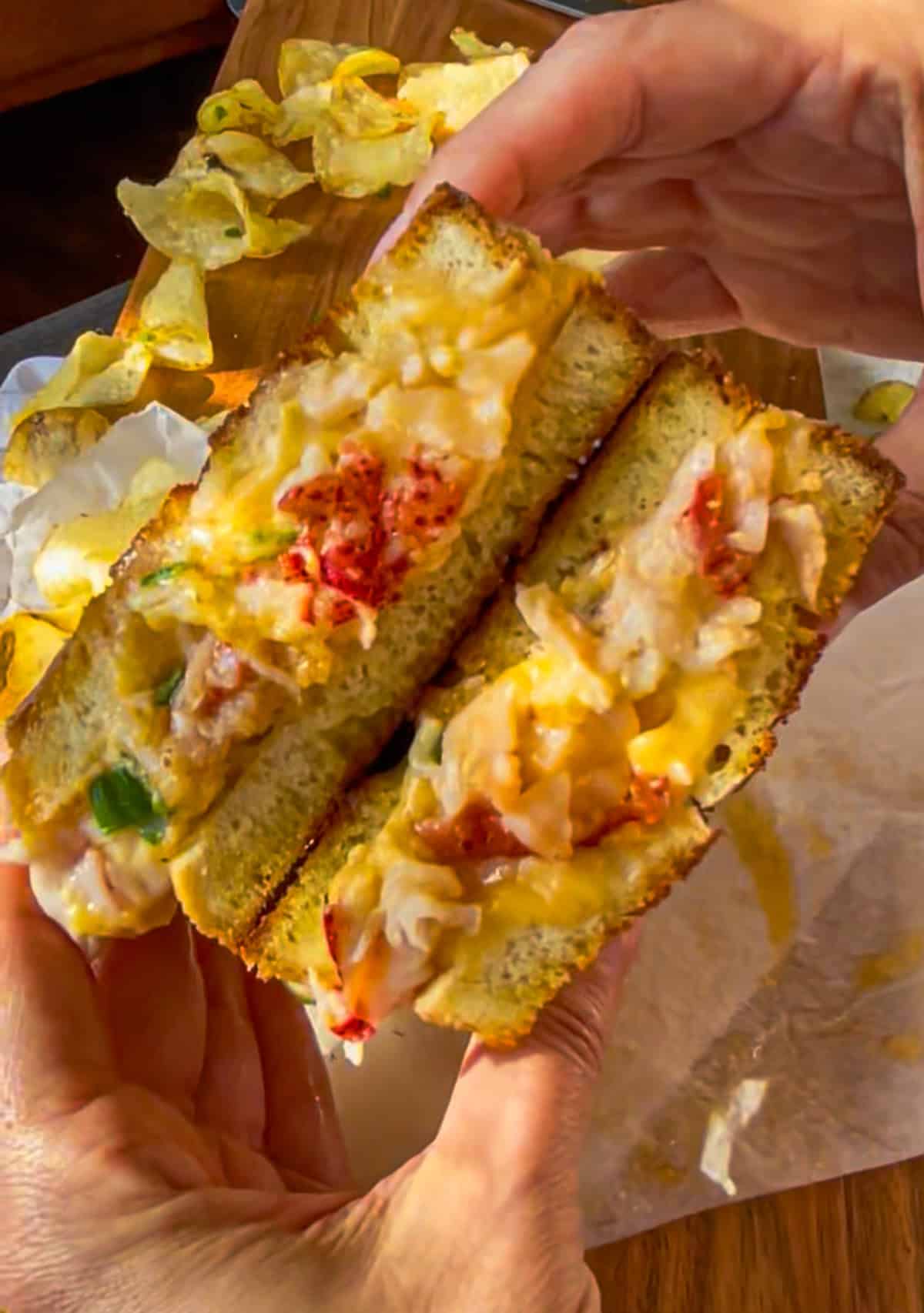 Lobster grilled cheese cut into half and held up.