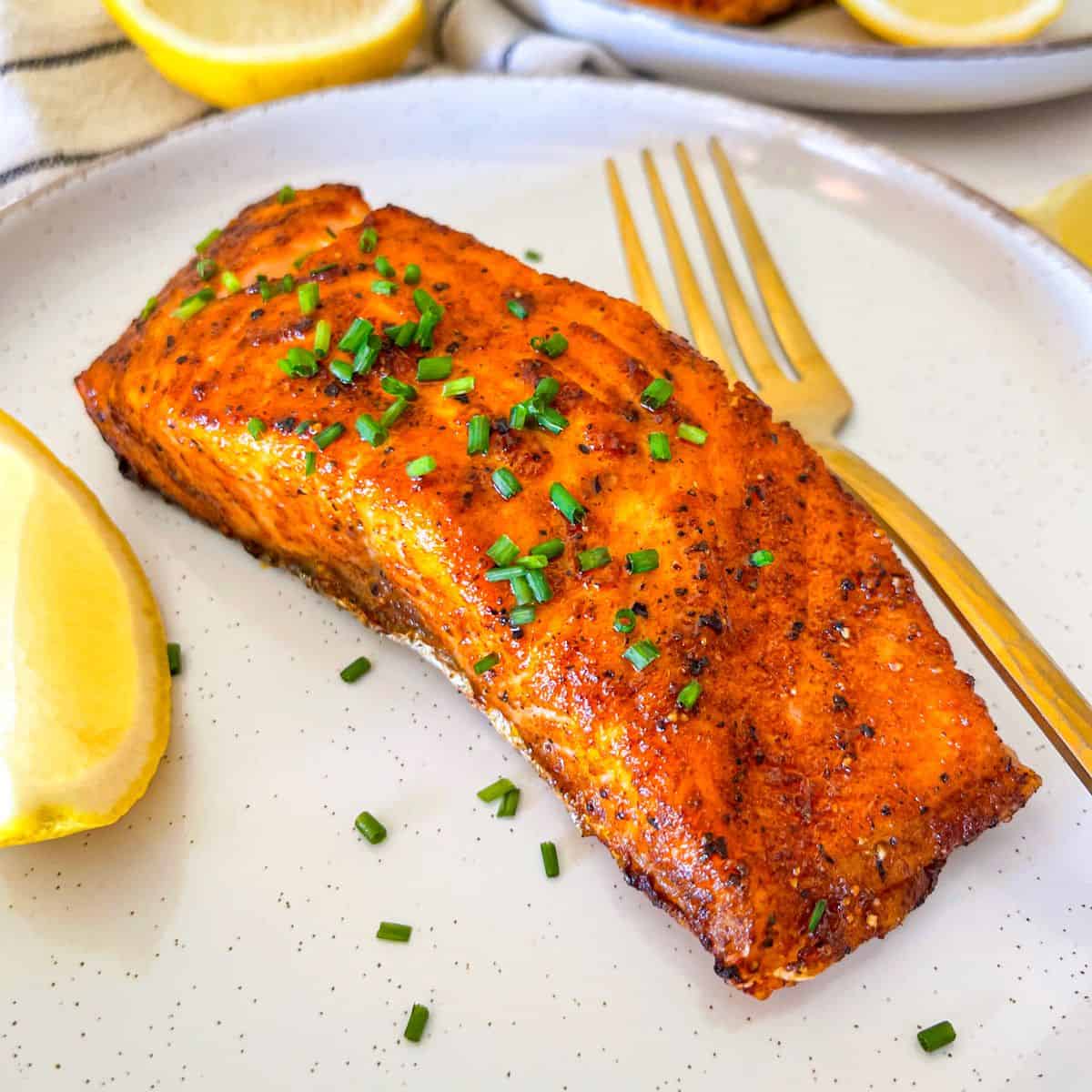 Air Fryer Salmon garnished with chives and lemon.
