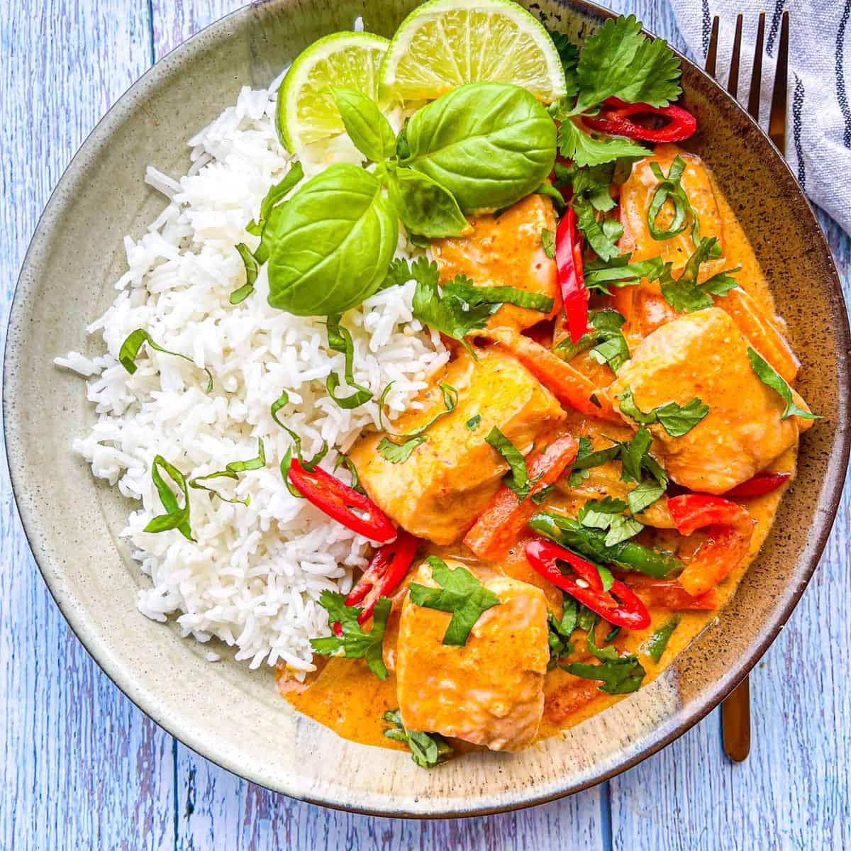30 Minute Thai Red Curry With Fish in a bowl with rice and limes.