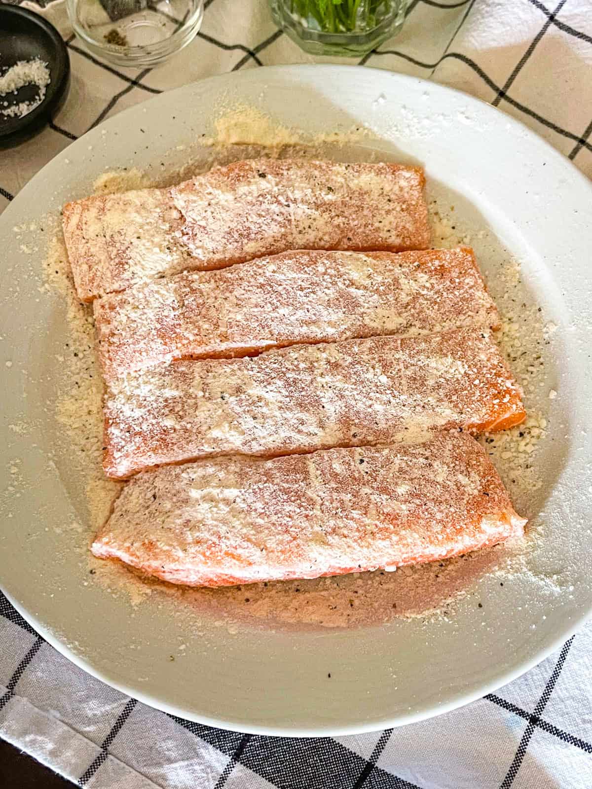 Seasoned salmon with seasoning on a white plate.
