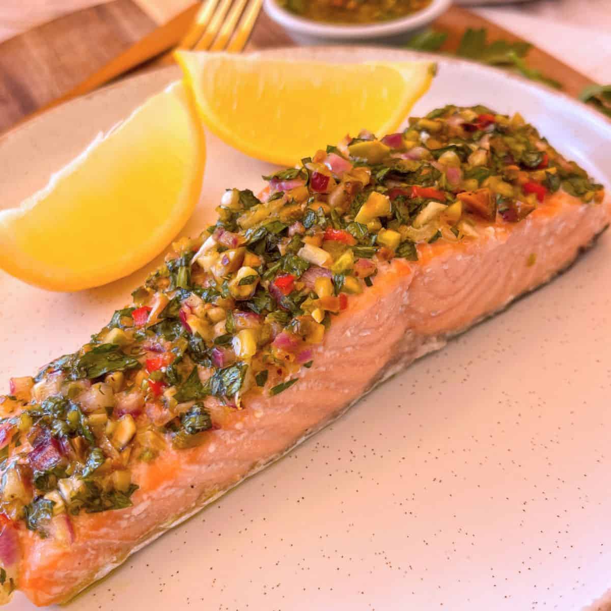 Salmon Chimichurri on a white plate with lemons.
