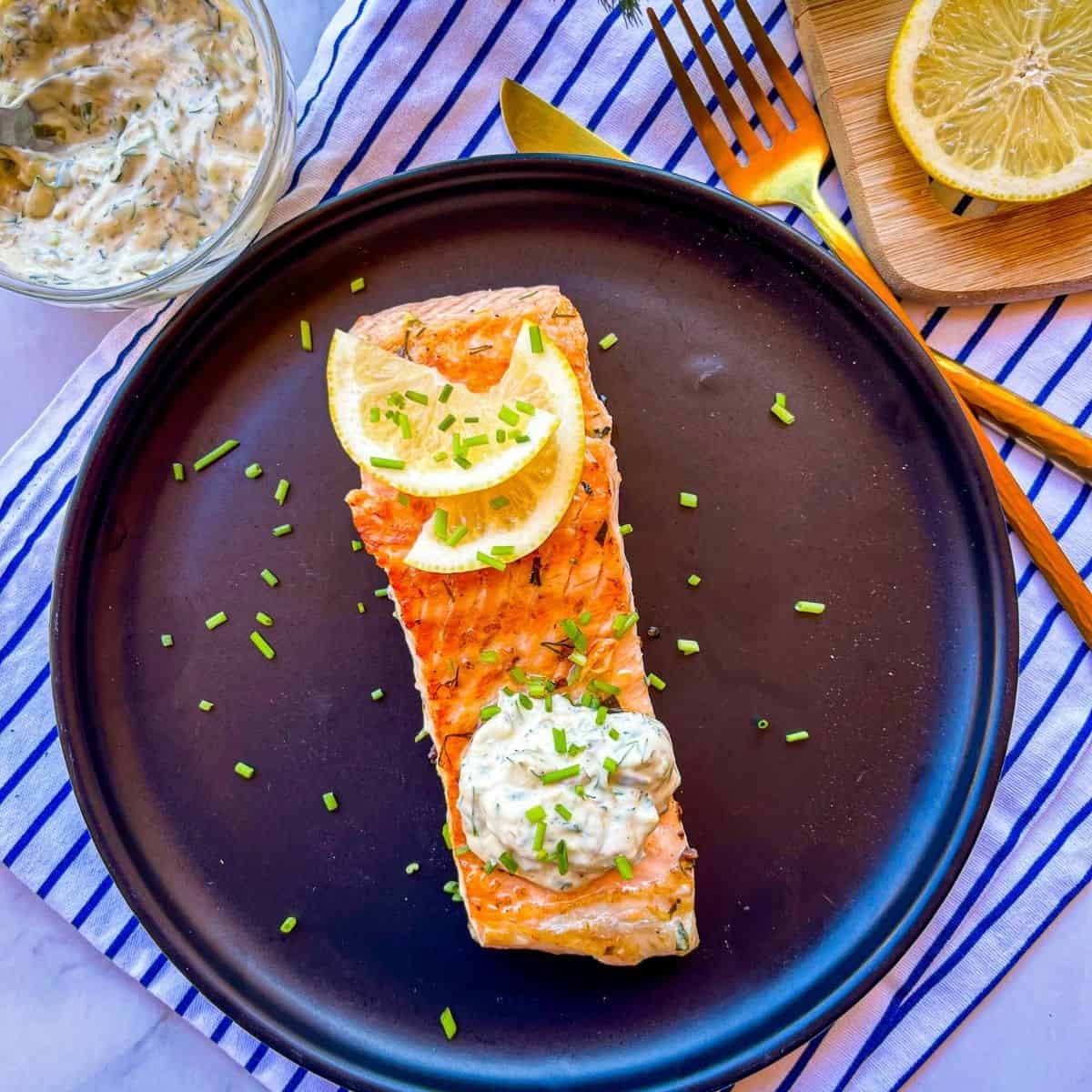 Pan-seared fish With herby mayonnaise on a black plate.
