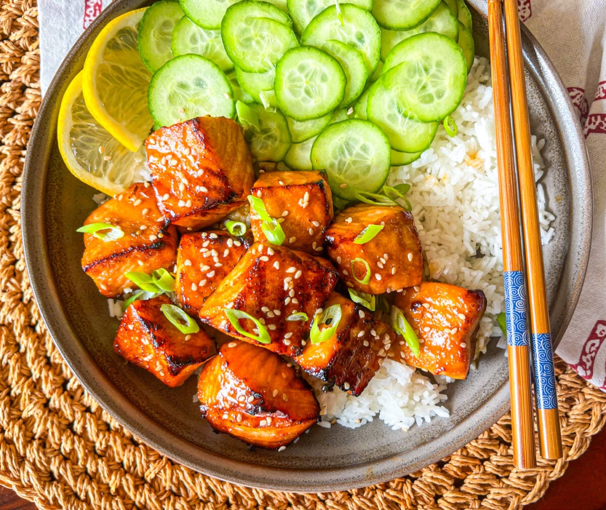 Hibachi Salmon bite over a ed of rice and side of cucumber.