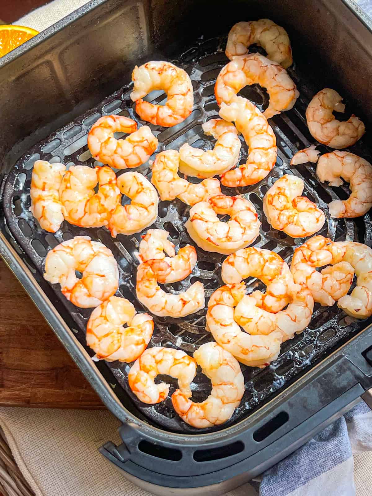 Cooked shrimp in air fryer basket.