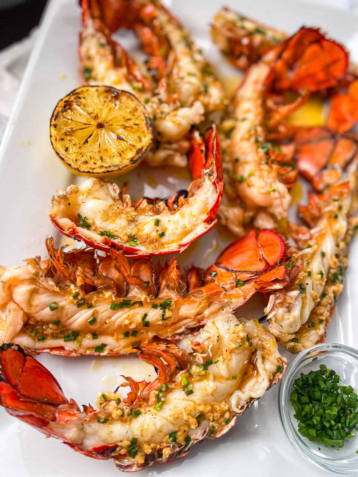 lobster tails cut in half and on a white platter.