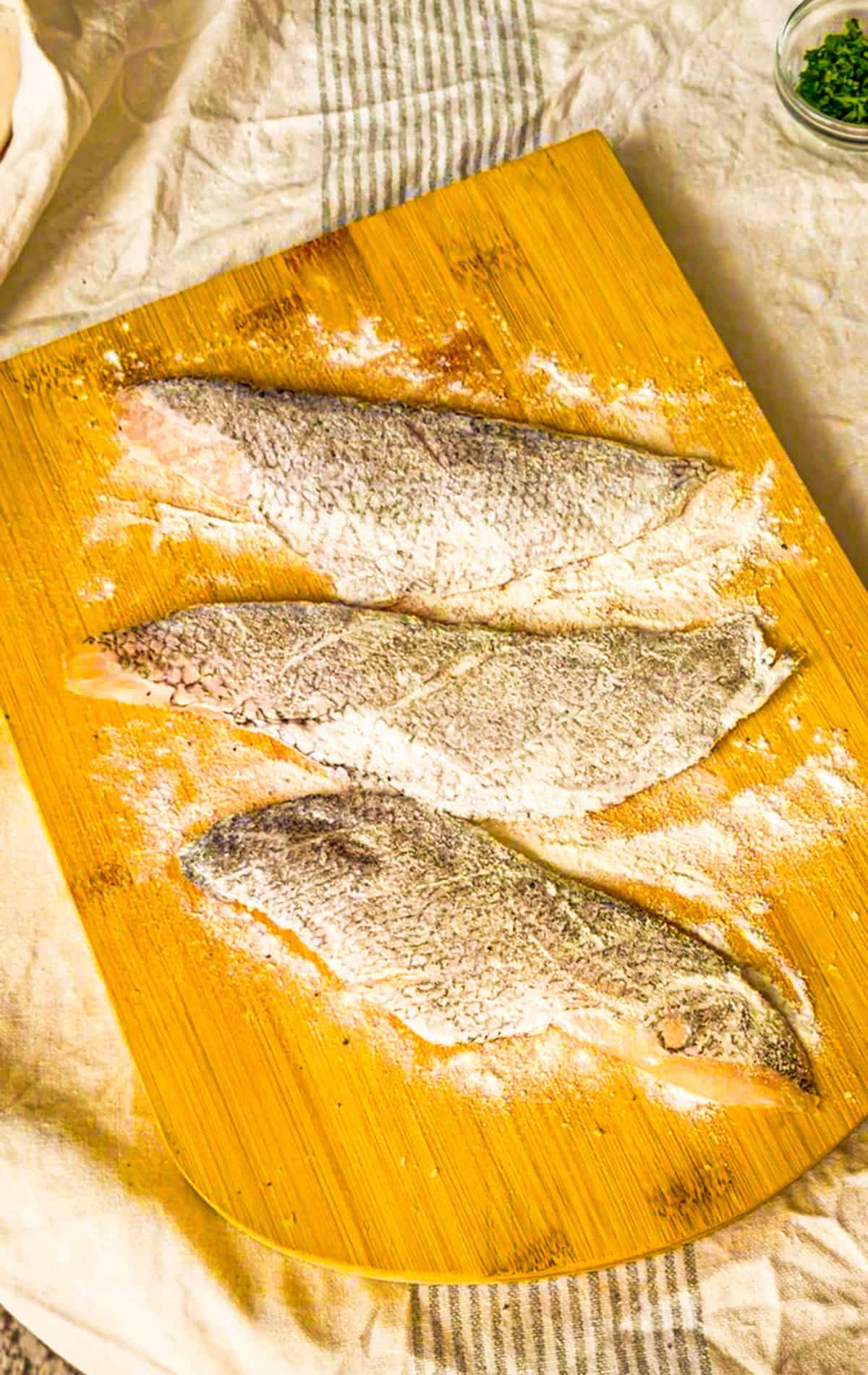fish dusted in flour on a board.