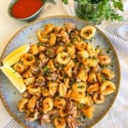 Plate of fried calamari next to some sauce.