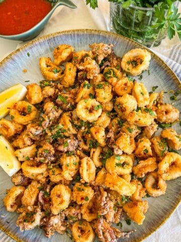 Plate of fried calamari next to some sauce.