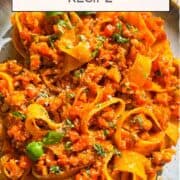 octopus pasta in a shallow bowl, pappardelle coated in tomato ragu with torn basil and Parmesan.