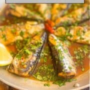 Portuguese garlic sardines in a sauce with cilantro, garlic and garnished with lemon.