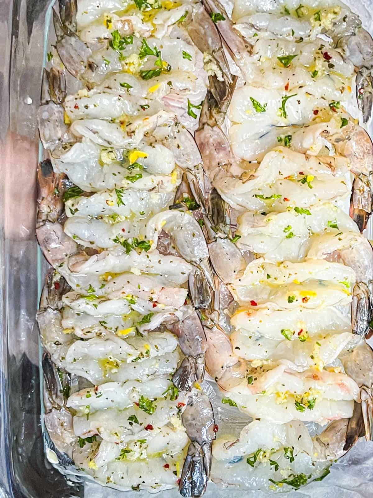 Marinated shrimp arranged in clear large dish.