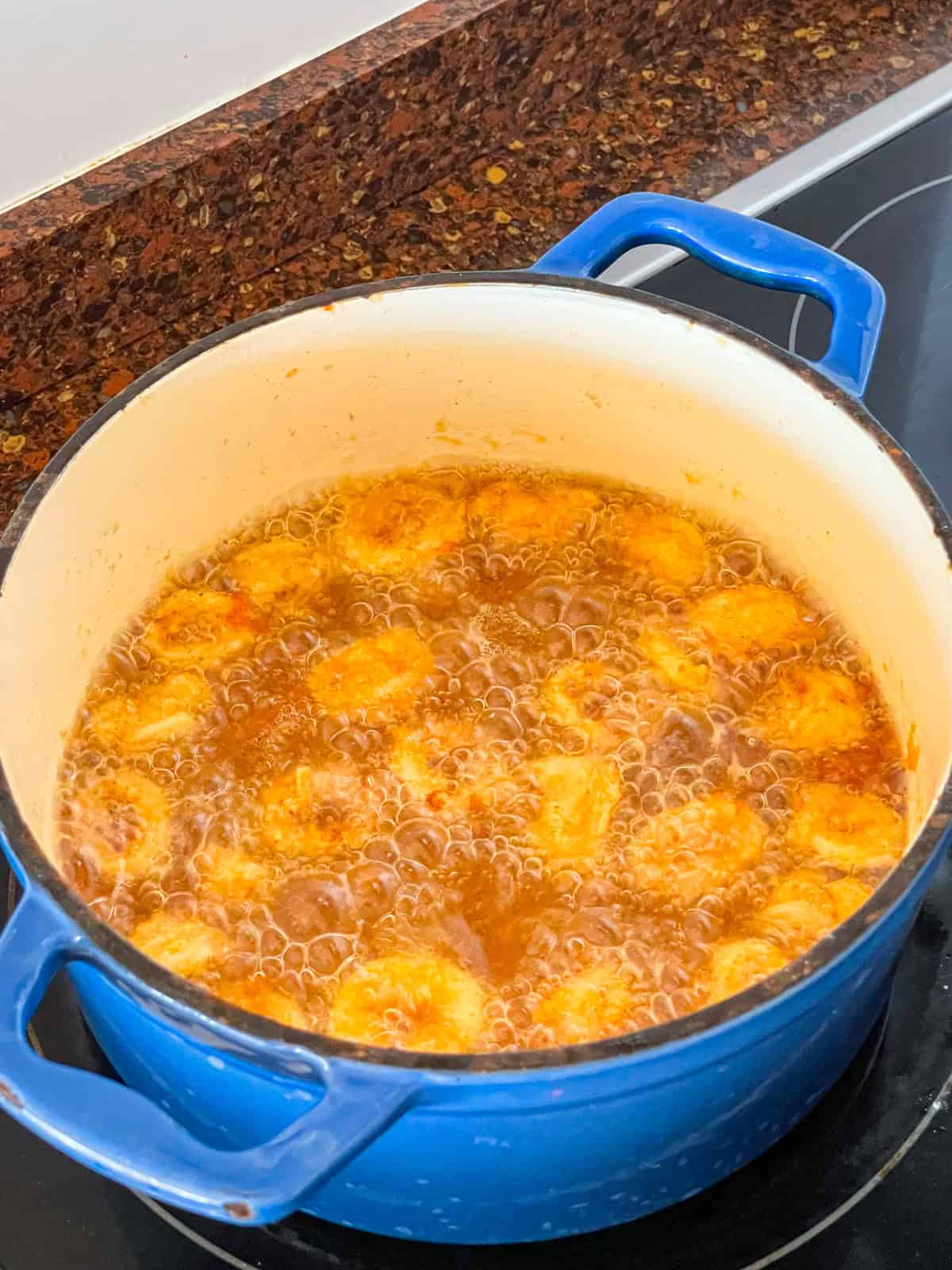 calamari rings frying in oil in a blue pot.