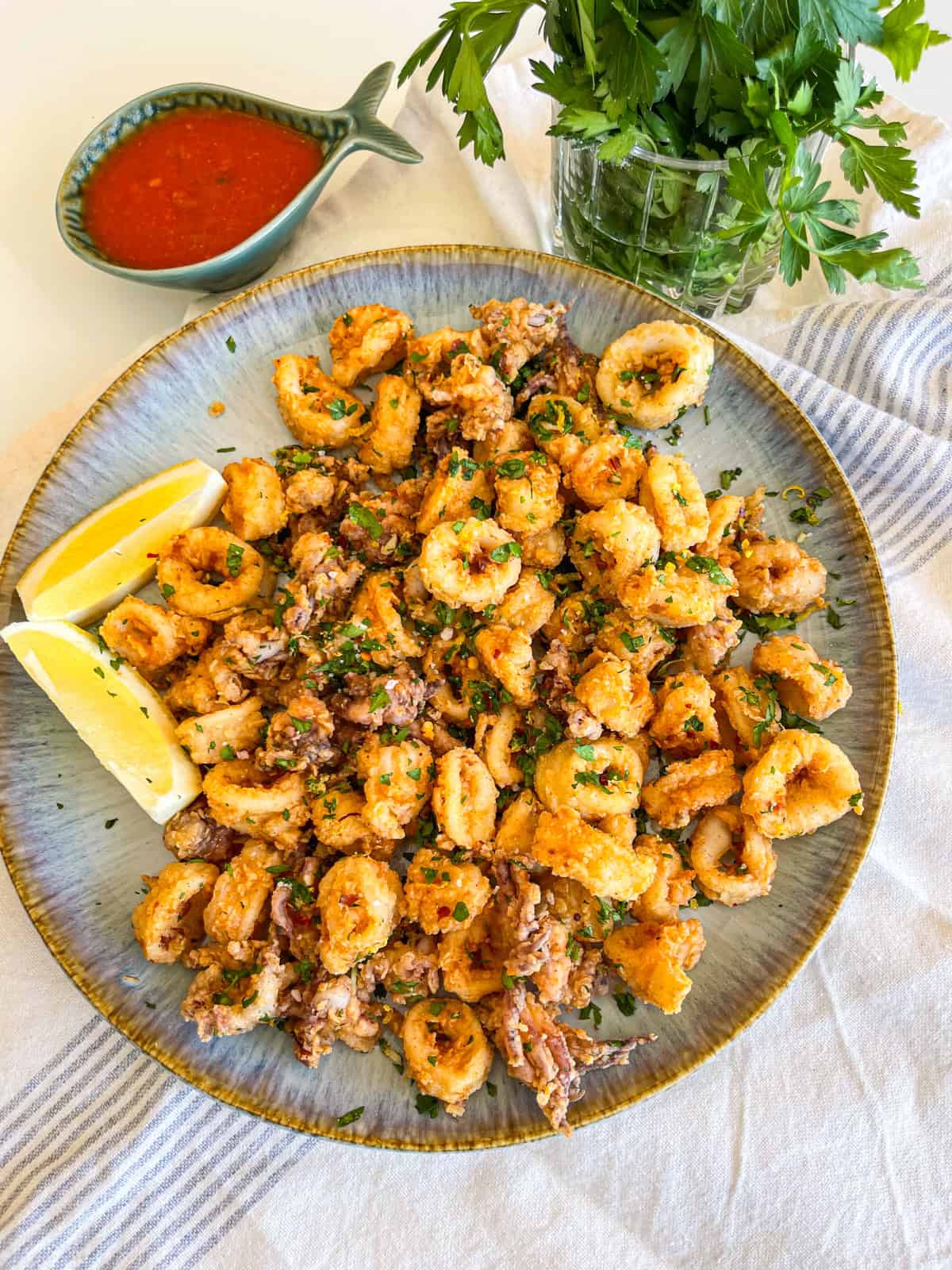 finished recipe on a plate with lemon wedges.
