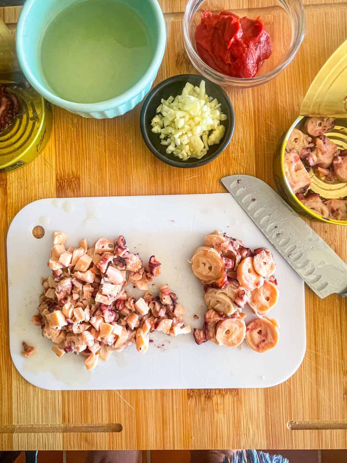 Octopus cut up on a board next to all ingredients.