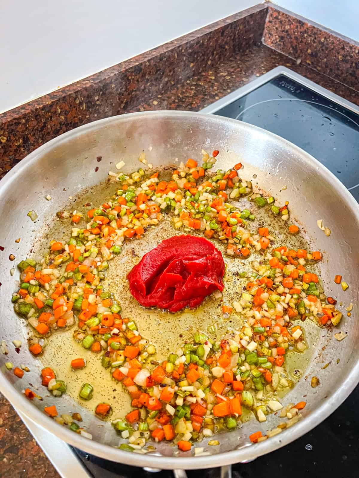 tomato paste darkening in a skillet with soffritto for octopus ragu.