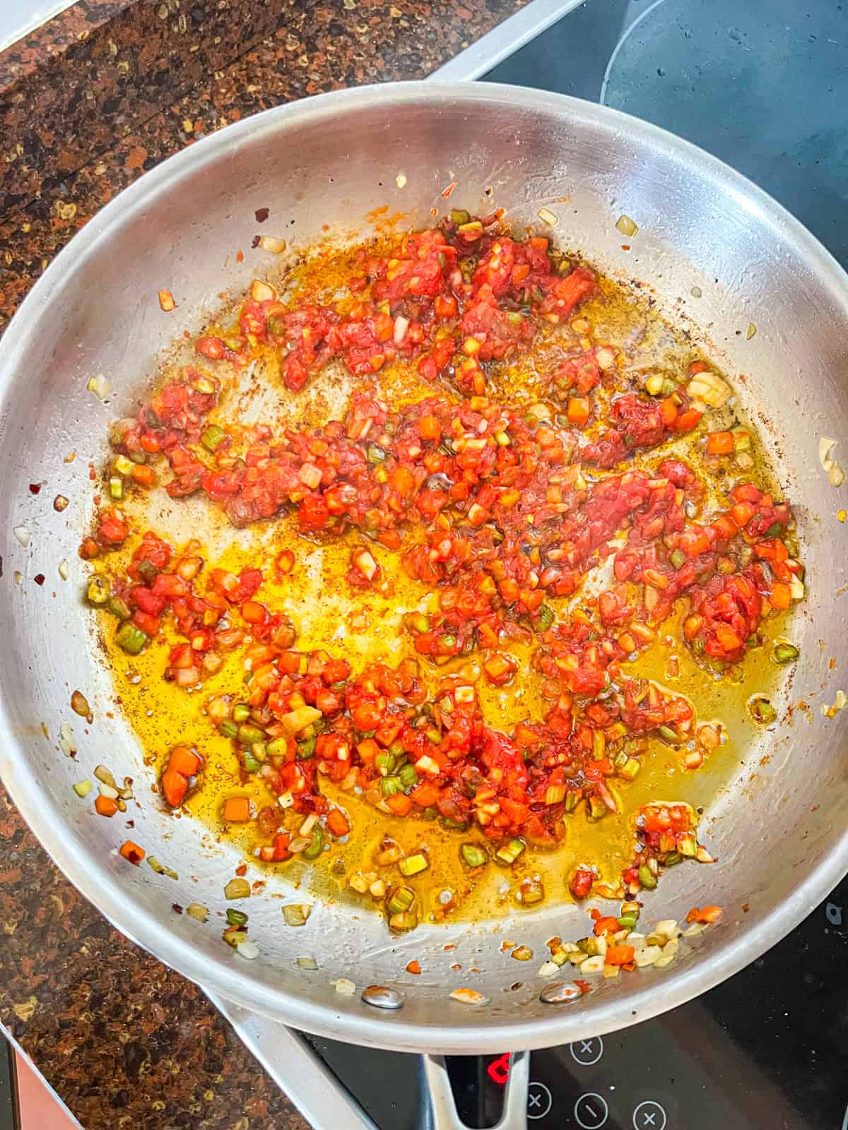 tomato paste and vegetables sizzling in skillet.