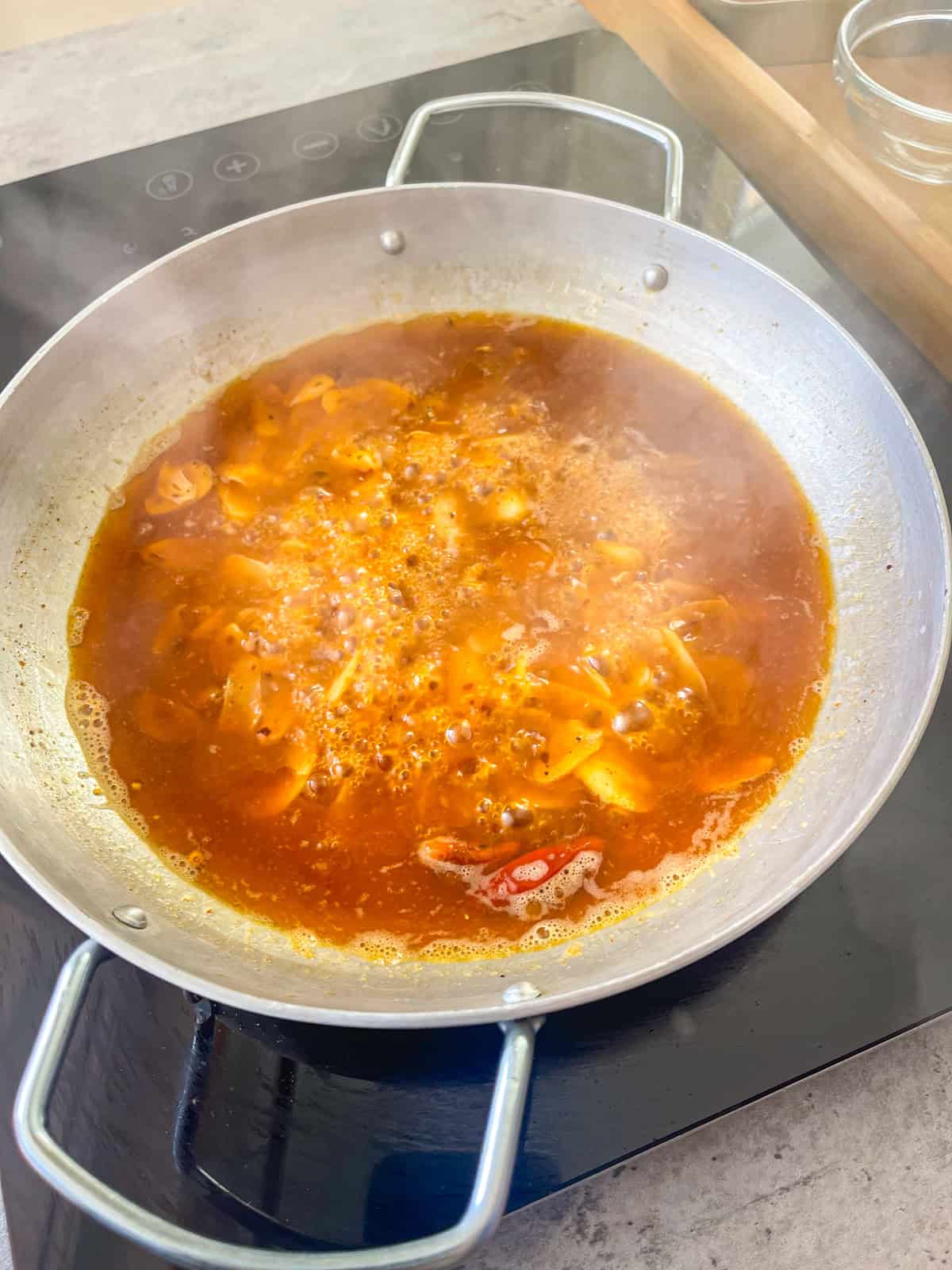 Garlic wine reduction in a skillet on a stove.