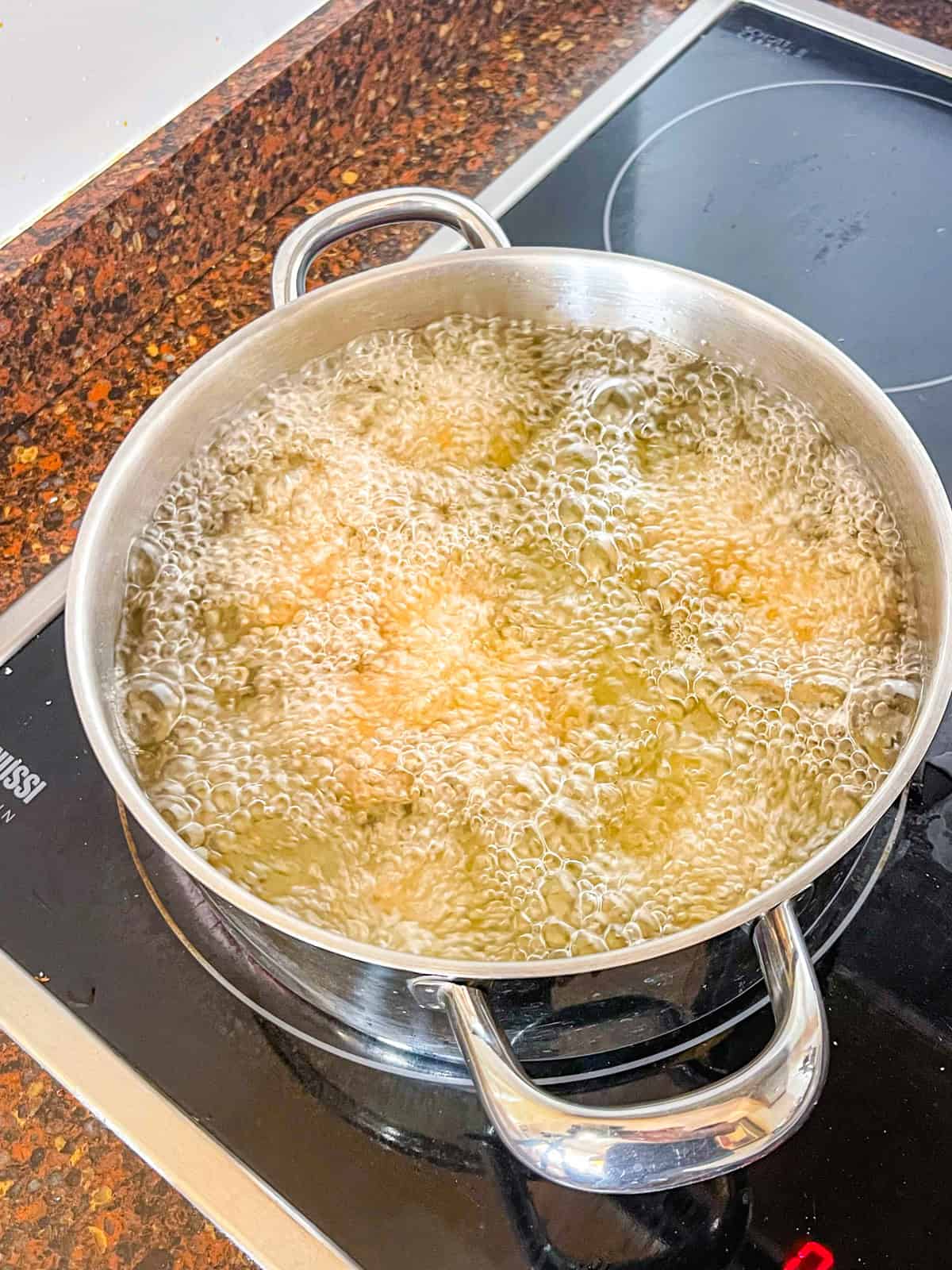 salmon croquetas frying in a Dutch oven.