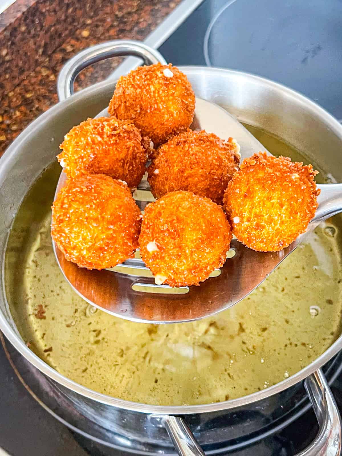 spanish croquetas fried in a Dutch oven and lifted to drain.